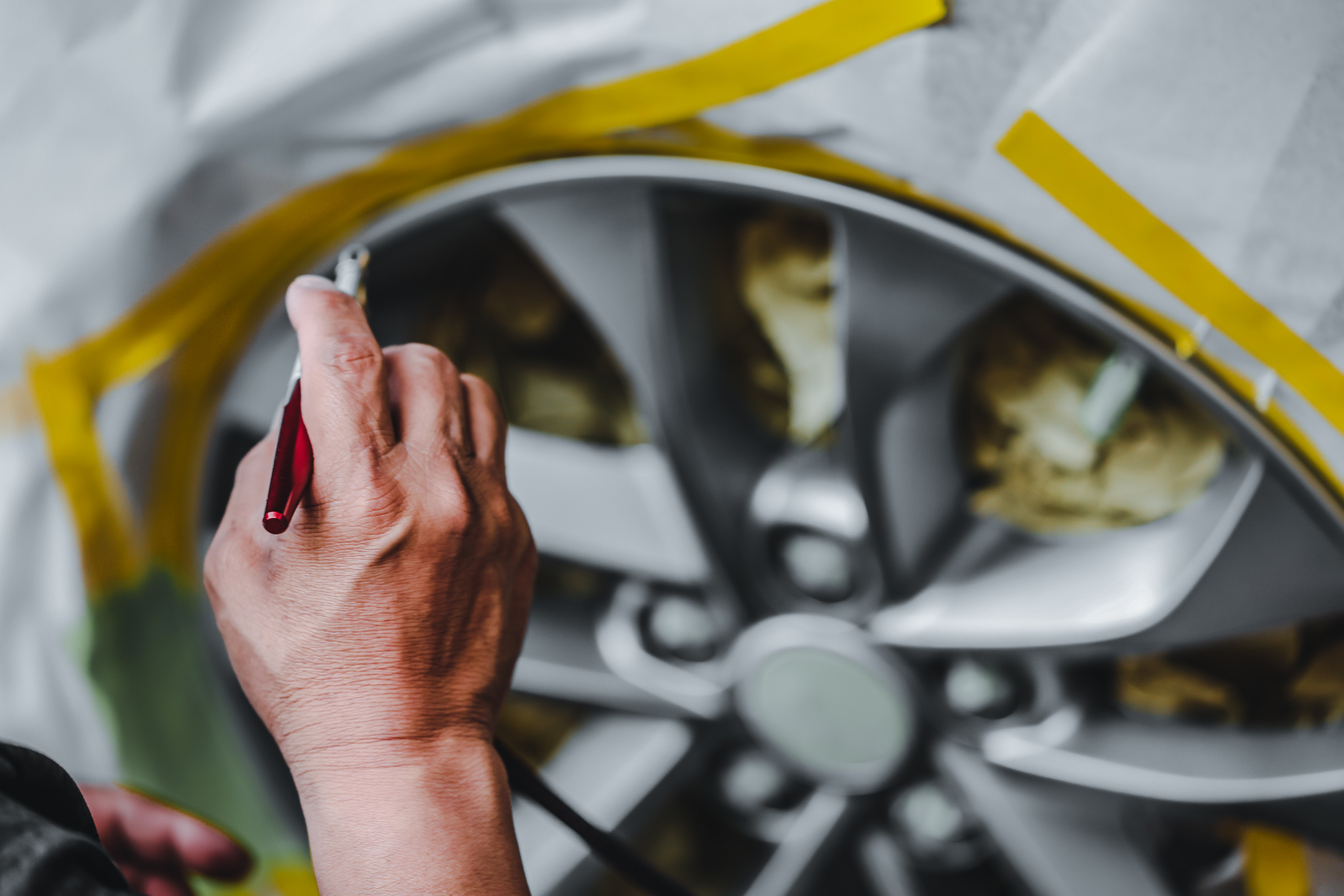 Alloy Wheel Repair Technician masked spraying wheel