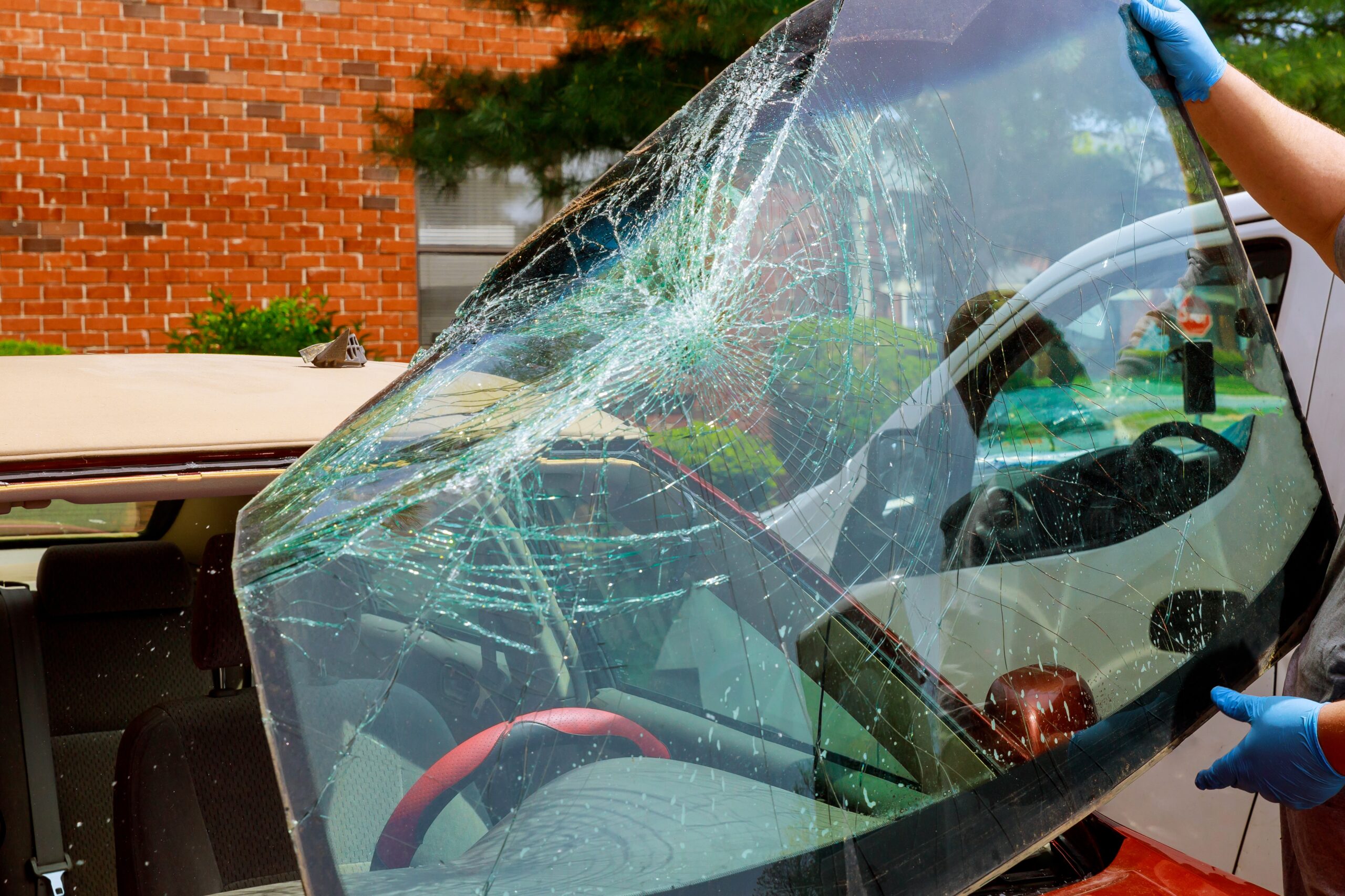 Broken windshield car special workers take of windshield replacement of a car in auto service from inside from accident of car.