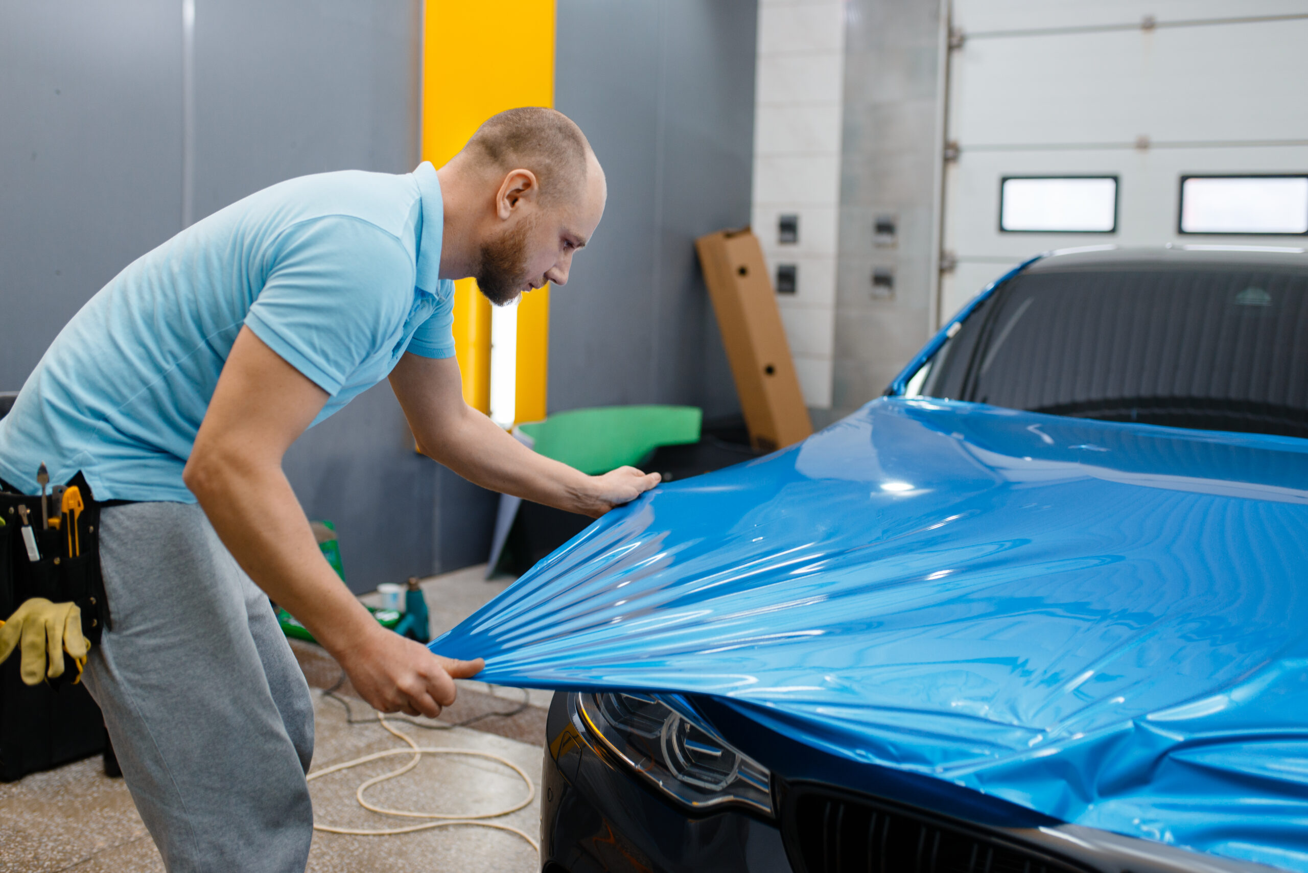 Car wrapper puts protective foil or film on hood vehicle wrapping.