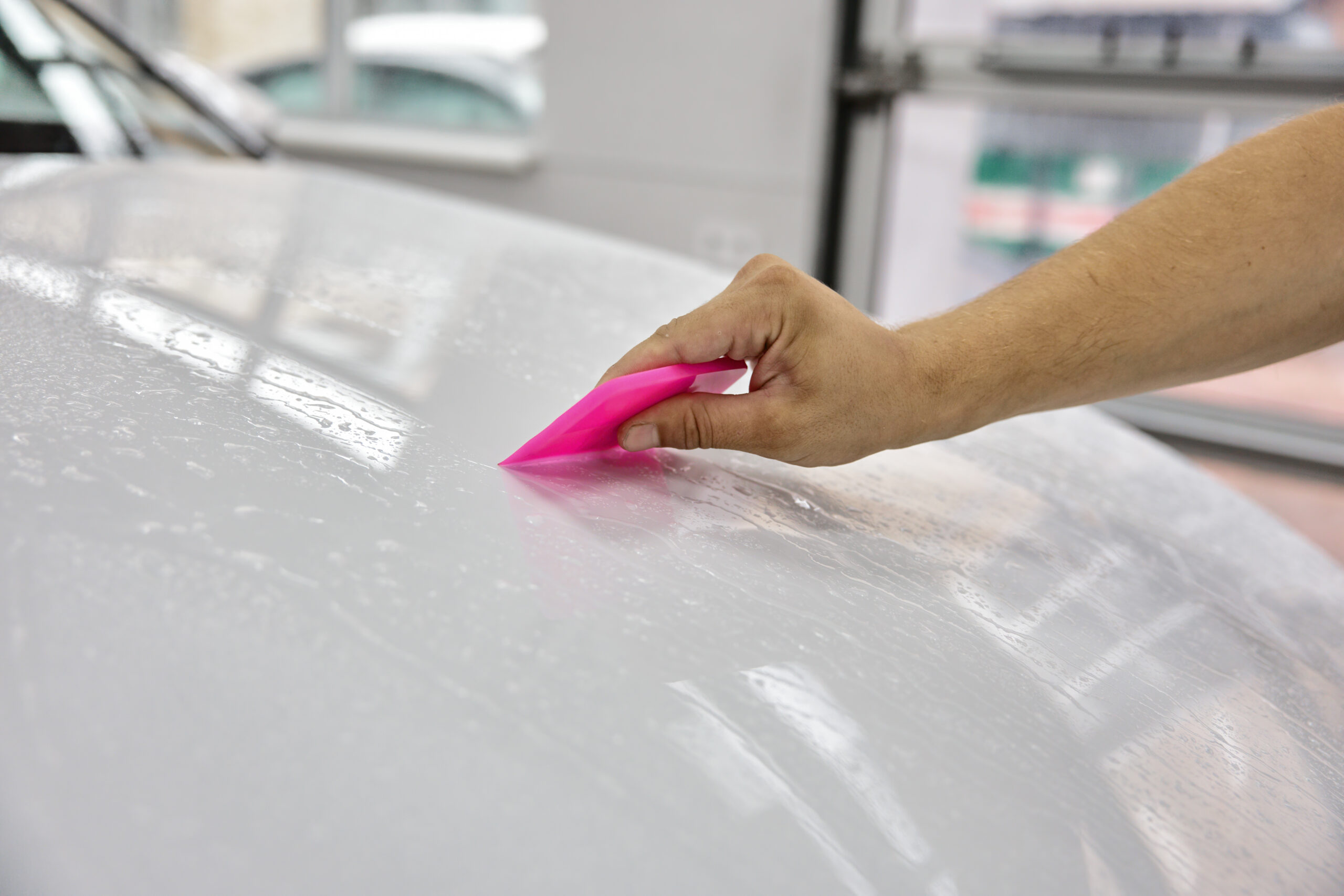 Closeup clear bra protection vinyl film installation on hood