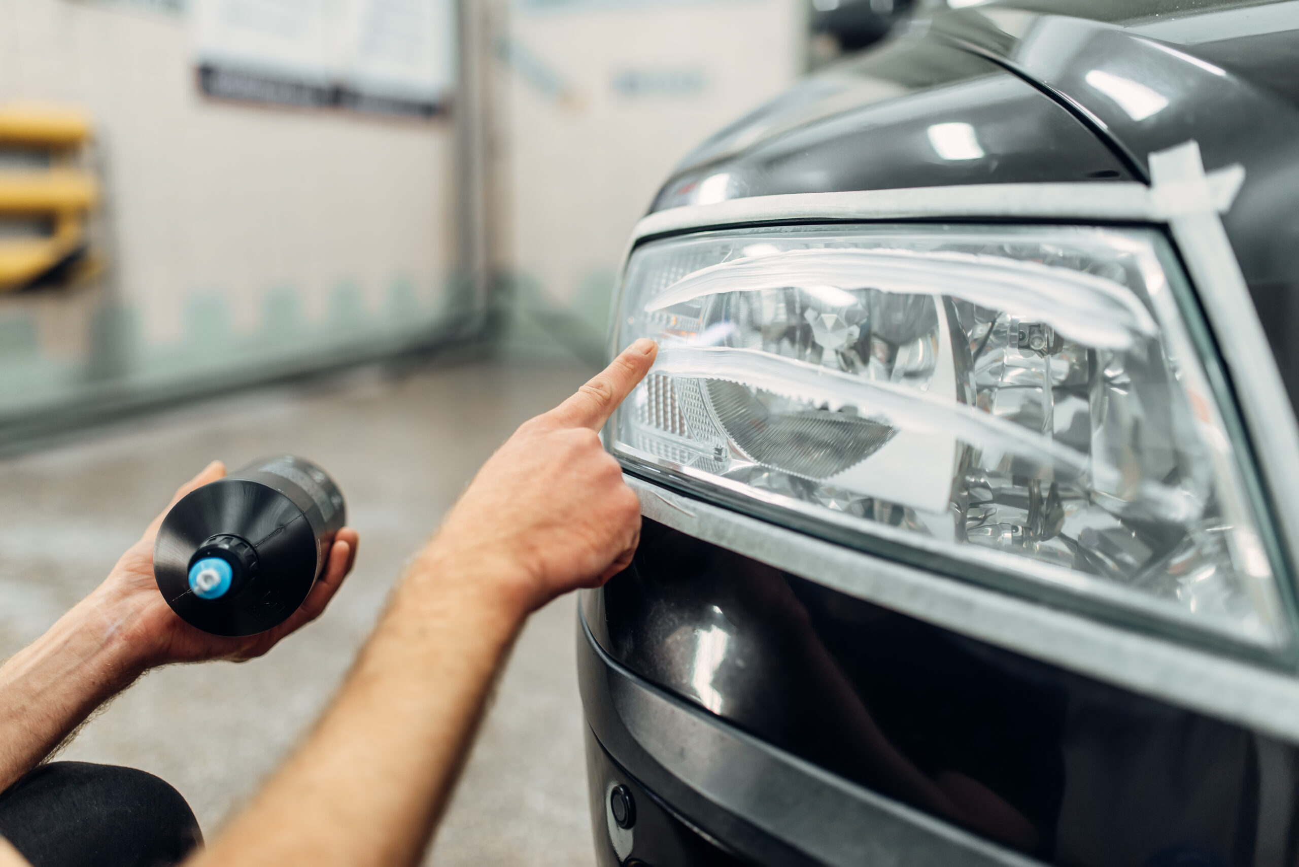 Detailing of headlight renewal, man smears polishing paste